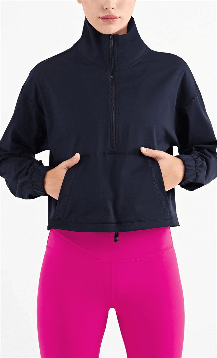 Woman wearing a black workout sports sweatshirt with pocket and pink leggings, showcasing a trendy fitness style.